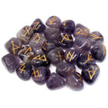 Set of 25 polished amethyst tumblestone rune stones with gold engraved runic symbols, displayed in a pile against a white background