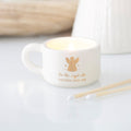 White ceramic tealight candle holder with gold angel figure and "For the angel who watches over me" gold script, styled with matches alongside
