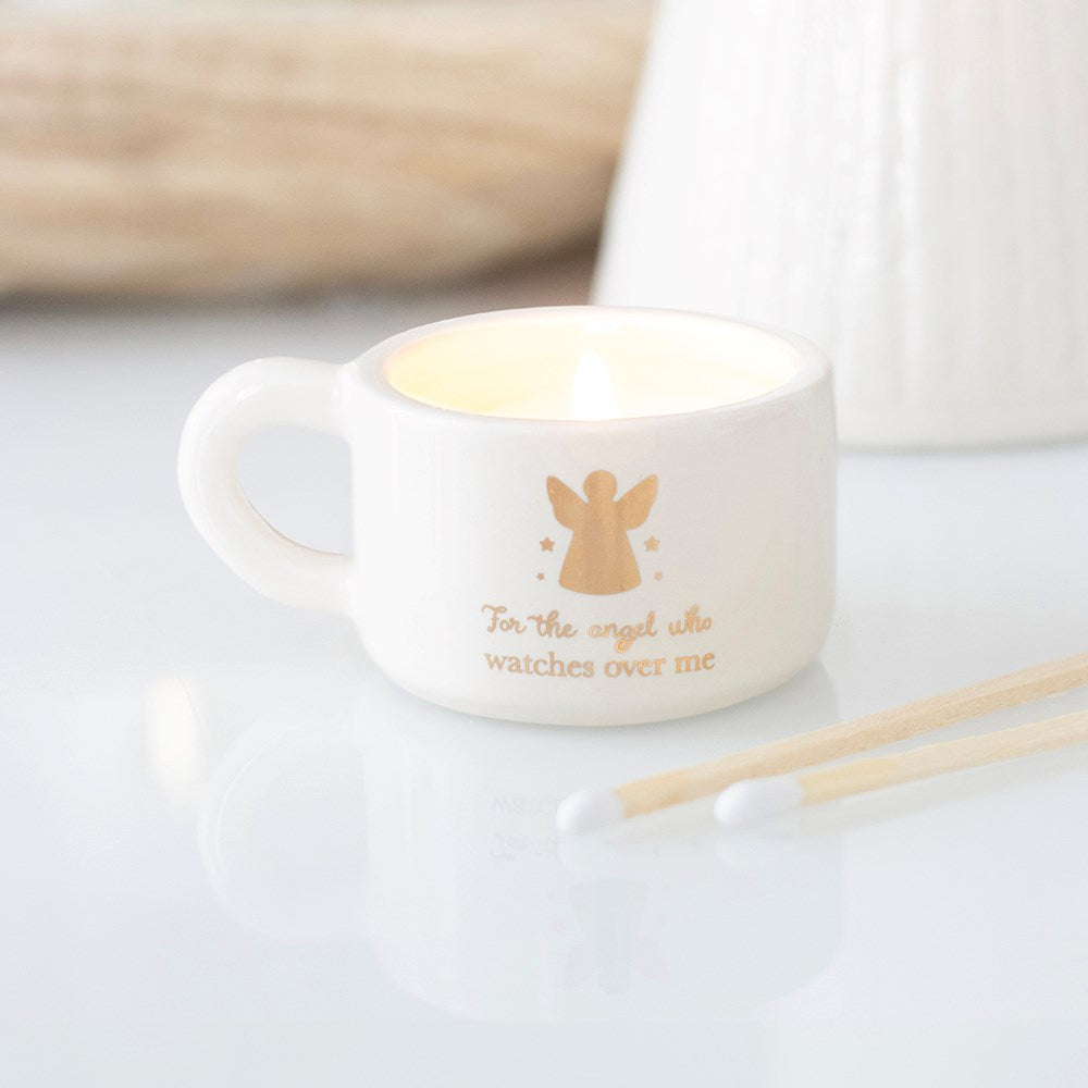 White ceramic tealight candle holder with gold angel figure and "For the angel who watches over me" gold script, styled with matches alongside