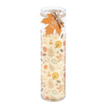 Tall glass tube pumpkin spice scented candle with autumn leaves and pumpkin pattern wrap, maple leaf gift tag and twine bow, on a white background