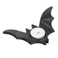 Black bat-shaped tealight candle holder with detailed wing texture, holding a white tealight candle on a white background