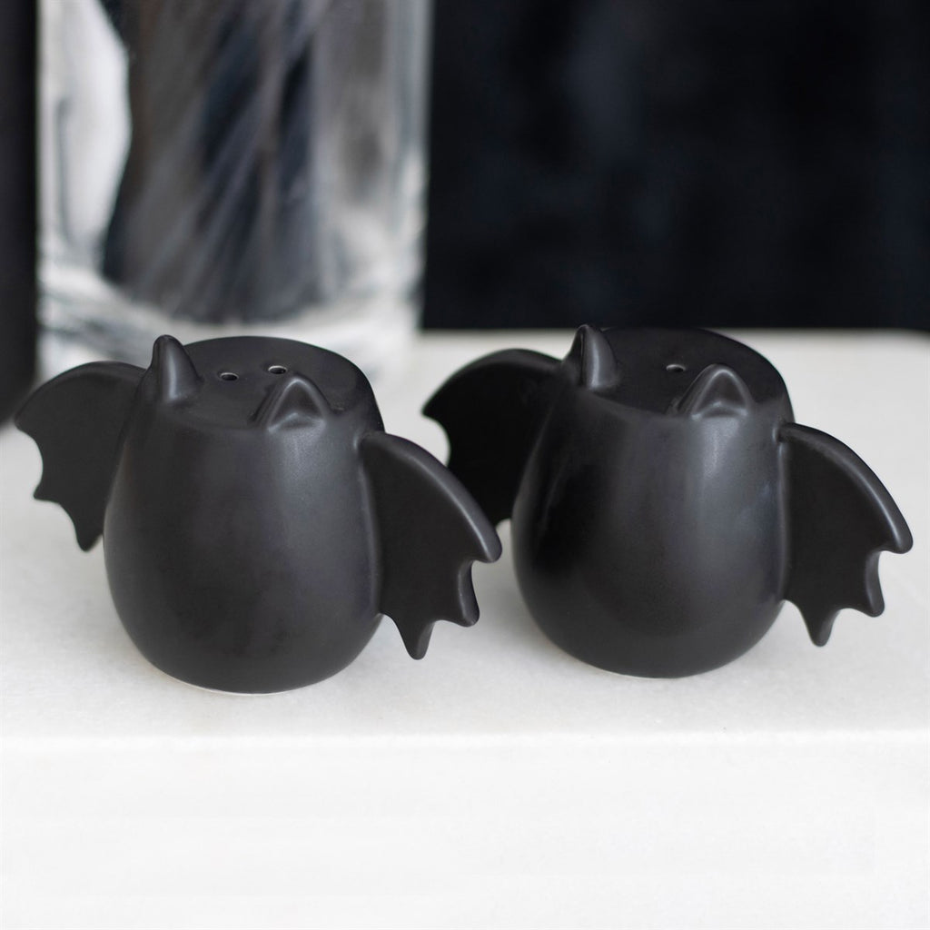 Black bat wing shaped salt and pepper shakers with gothic decorative design for kitchen or dining table use.