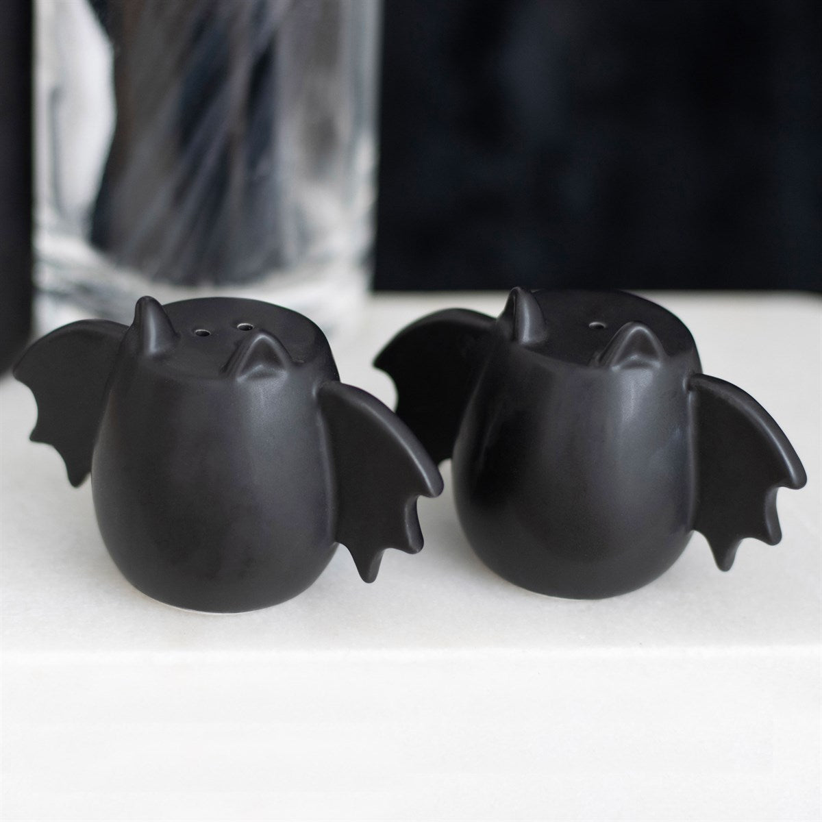 Black bat wing shaped salt and pepper shakers with gothic decorative design for kitchen or dining table use.