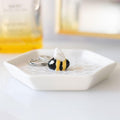 Ceramic honeycomb design bee trinket dish with 3D bumblebee detail, shown with rings on a white surface