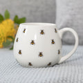 Rounded ceramic mug featuring decorative bee print pattern with nature-inspired design.
