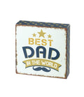 Small square wooden block plaque with vintage distressed finish reading "Best Dad In The World" in gold and navy lettering with stars and moustache detail, on a white background