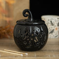 Black ceramic pumpkin oil burner and wax warmer with folk-inspired cut-out floral and star details, featuring a decorative curled lid.