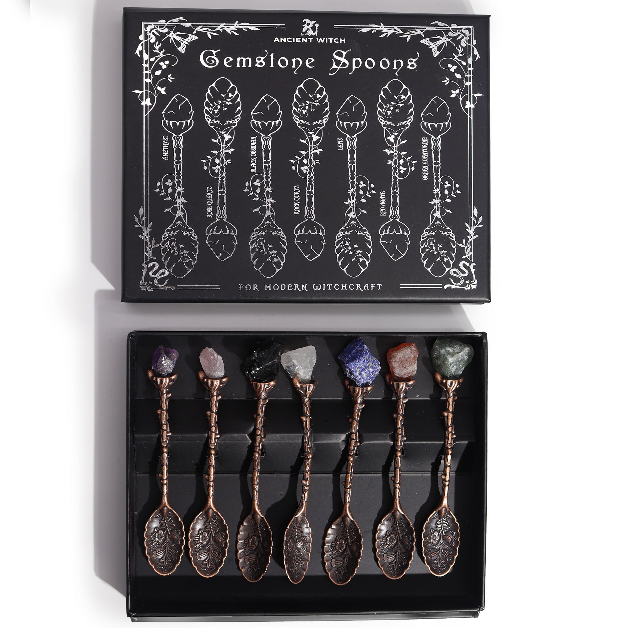 Set of 7 bronze witch spoons with gemstone crystal handles arranged together, mystical themed decorative cutlery set.