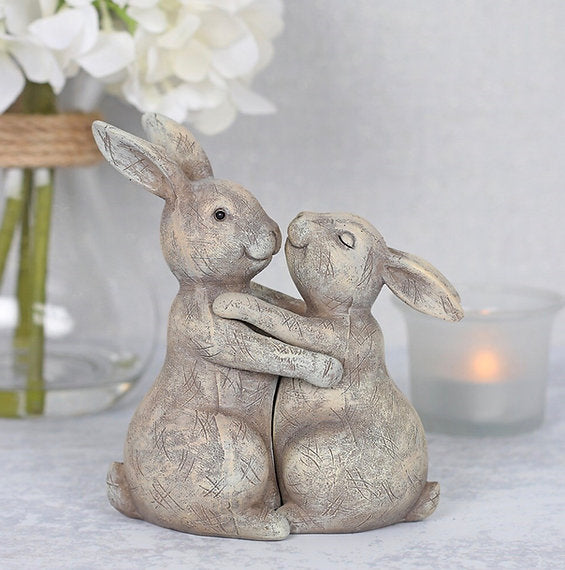 Decorative ornament featuring two cuddling rabbits embracing nose-to-nose, accompanied by a sentiment card reading “You Make My Heart Thump” and a heartfelt message about love and companionship.