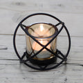 Black iron spherical candle holder with a single amber glass votive cup, on a rustic wooden surface