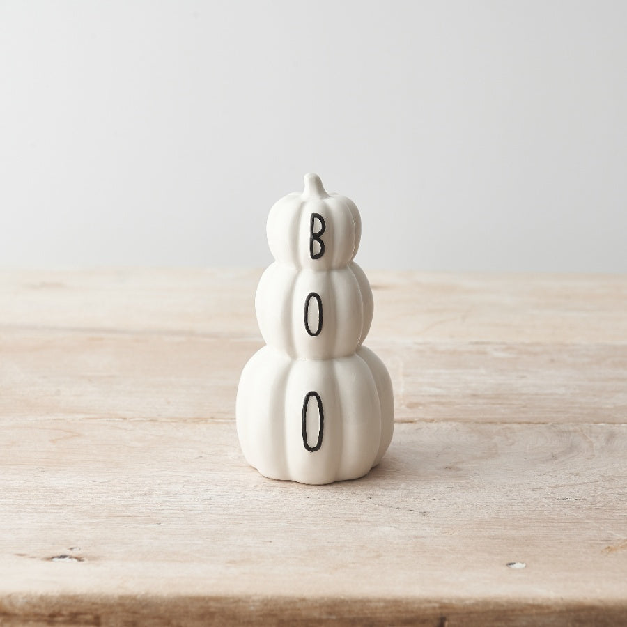 White ceramic stacked pumpkin ornament with "BOO" lettering across three tiers, displayed on a wooden surface

