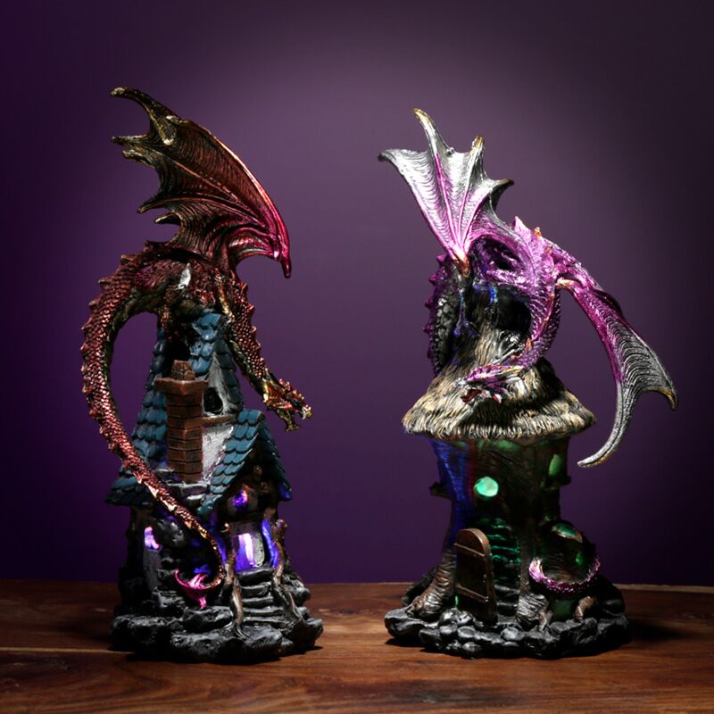 Dark Legends LED dragon house light-up ornaments showing red and purple dragon variants perched on illuminated fantasy castle bases against a purple background