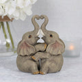 Decorative elephant couple embrace figurines featuring affectionate pose and detailed ornamental finish.