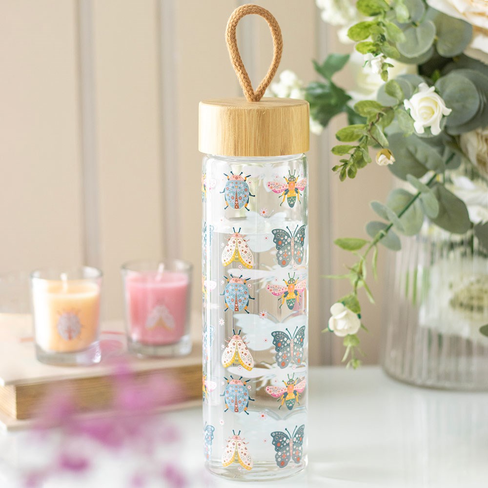 Pastel glass water bottle featuring floral and bug themed decorative pattern with nature-inspired design.