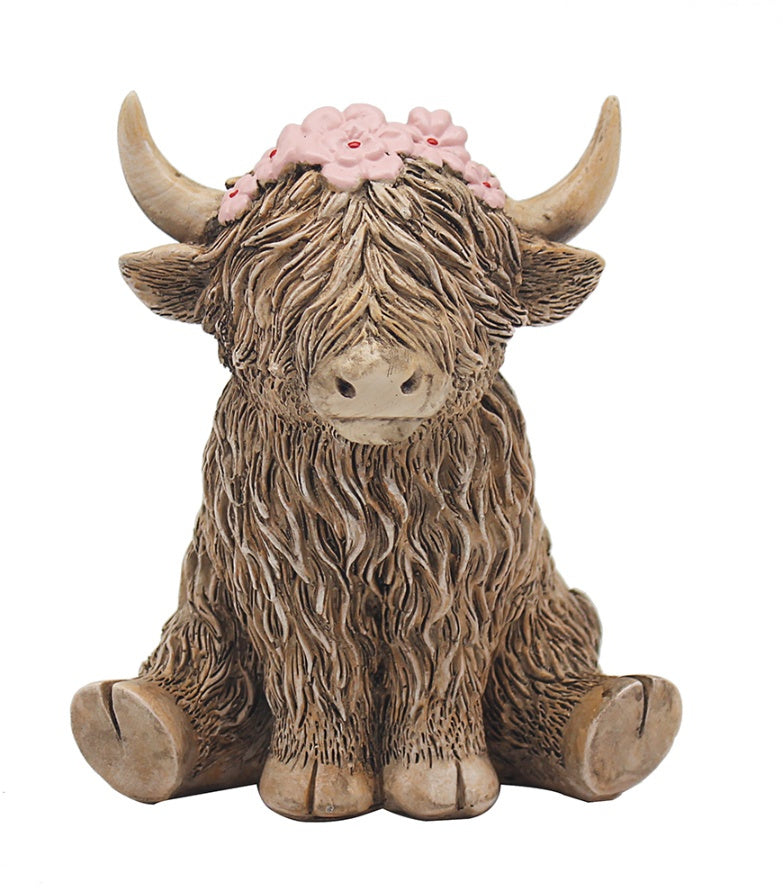 Ceramic highland cow figurine with a floral headband on a white background