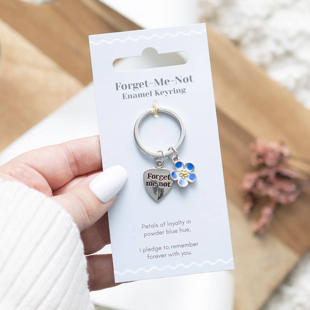 Metal keyring featuring a forget-me-not flower charm with blue enamel detailing and attached keyring loop.