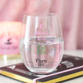 Clear stemless wine glass printed with Good Witch, Bad Witch and Pure Evil fill level markers, styled on a book with a pink candle and notebook in the background
