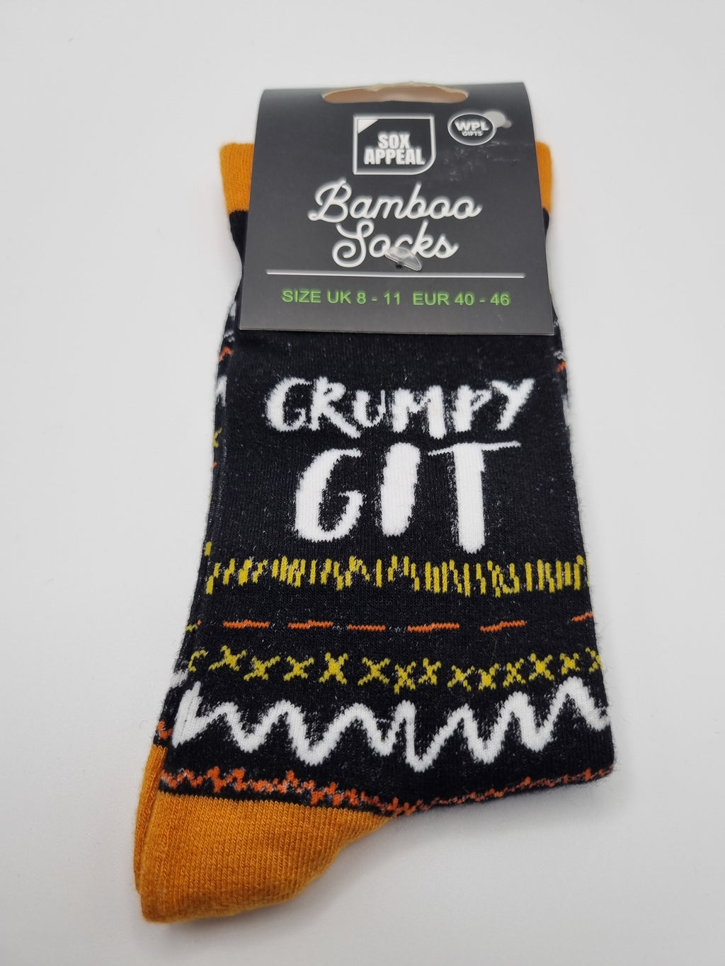 Black Grumpy Git novelty men's bamboo socks with white bold text, yellow and orange fairisle pattern, and mustard yellow cuffs and toes, UK size 8–11, shown in packaging