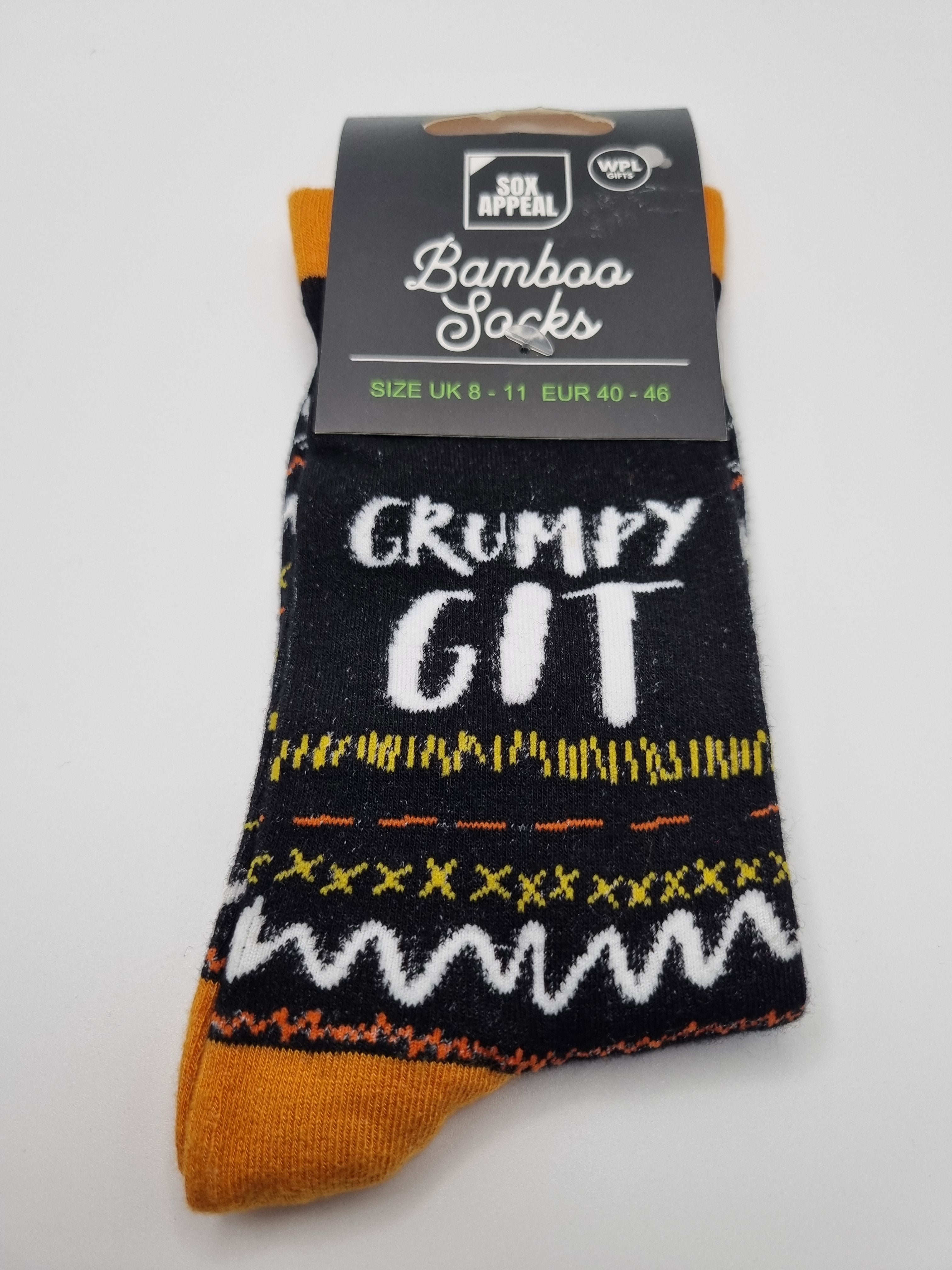 Black Grumpy Git novelty men's bamboo socks with white bold text, yellow and orange fairisle pattern, and mustard yellow cuffs and toes, UK size 8–11, shown in packaging