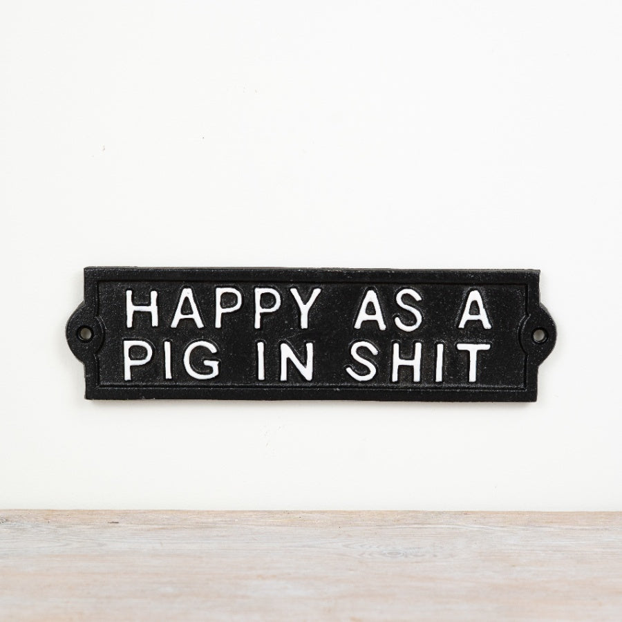 Cast iron sign reading “Happy As A Pig In Sh1t” with rustic vintage-style decorative finish.