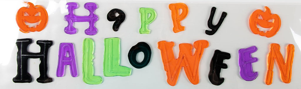 Reusable Happy Halloween window gel decoration letters and pumpkins in orange purple green and black laid out on white backing sheet