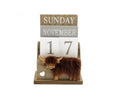 Wooden perpetual block calendar with Highland cow figurine on the base, displaying Sunday November 17, on a white background

