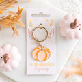 Alloy and enamel pumpkin keyring featuring a pastel orange pumpkin charm on a gold-tone key ring, displayed on branded backing card.
