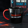 Black ceramic mug with a red handle featuring the words “Mornings Are For Coffee” in bold red and white lettering on the front.