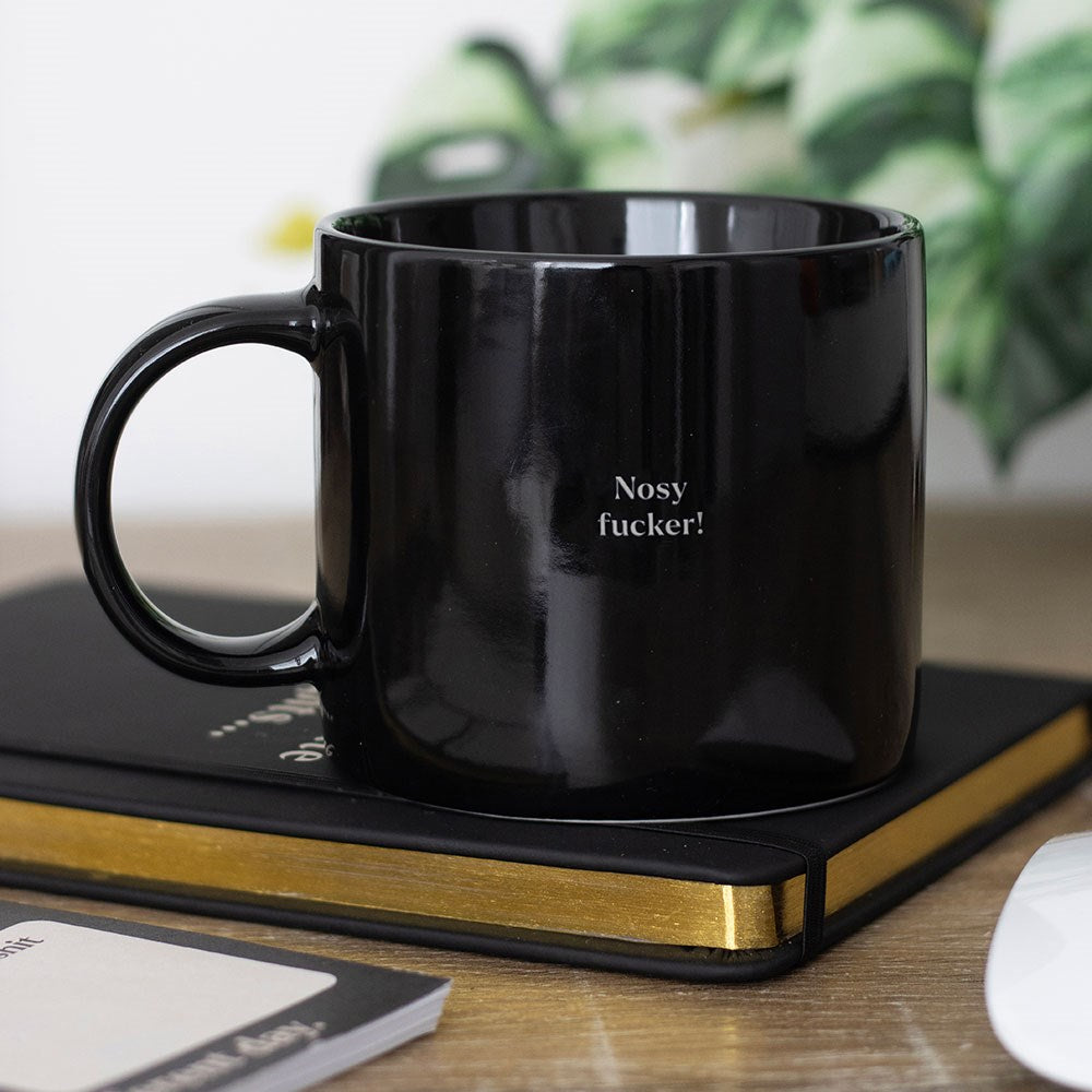 Ceramic mug featuring “Nosy F*cker” text with bold humorous design for tea, coffee, and hot drinks.