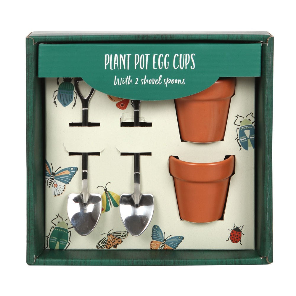 Plant Pot Egg Cup Set gift box containing two terracotta-style ceramic egg cups and two stainless steel garden shovel spoons, with a bug and butterfly illustrated insert
