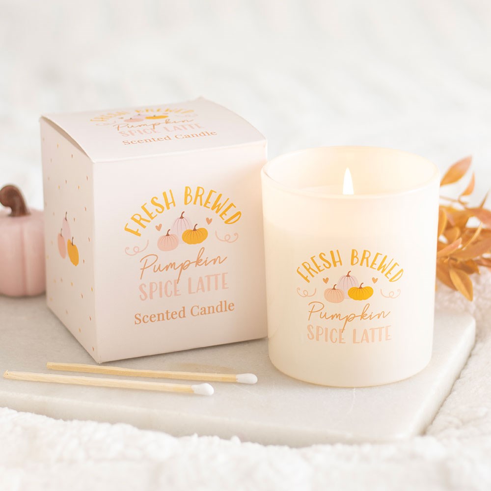Frosted glass pumpkin spice latte scented candle with gift box, styled with matches, a pink pumpkin and autumn leaves on a white tray