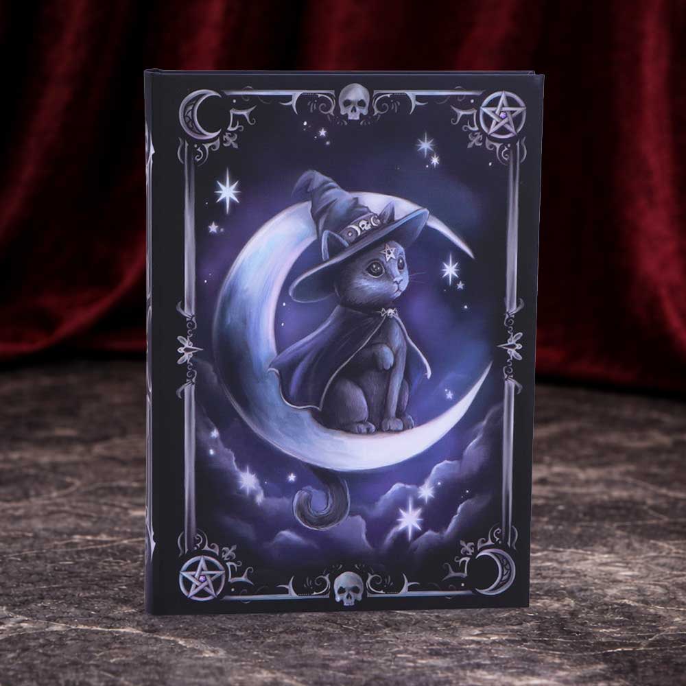 Cult Cuties Purrah A5 hardback journal — black cover featuring a witchy cat in a pointed hat seated on a crescent moon, surrounded by stars, skulls and pentagrams in purple and silver tones