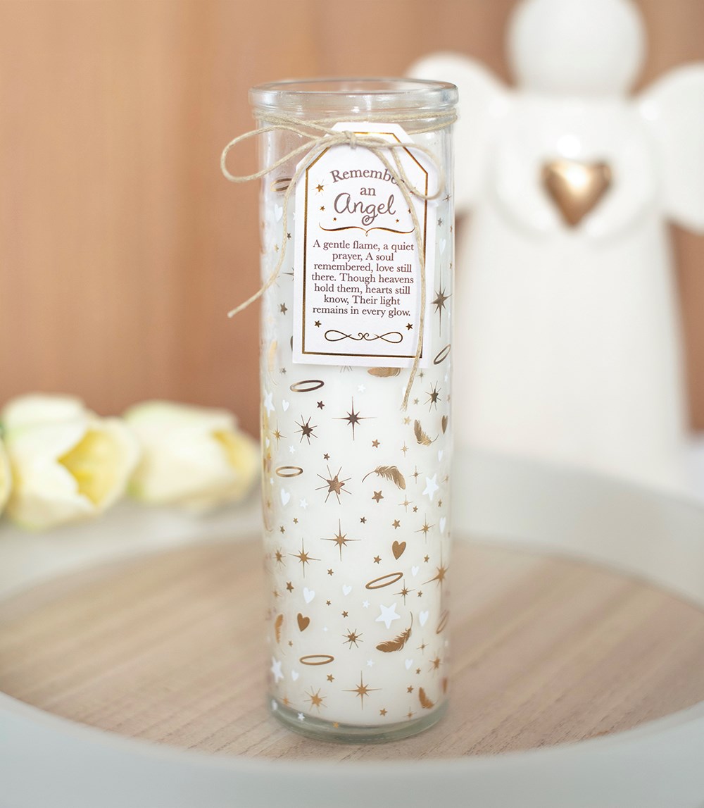 Tall glass tube scented candle with gold stars, feathers and hearts design, tied with twine and a Remember An Angel gift tag, styled with white angel figurines in the background