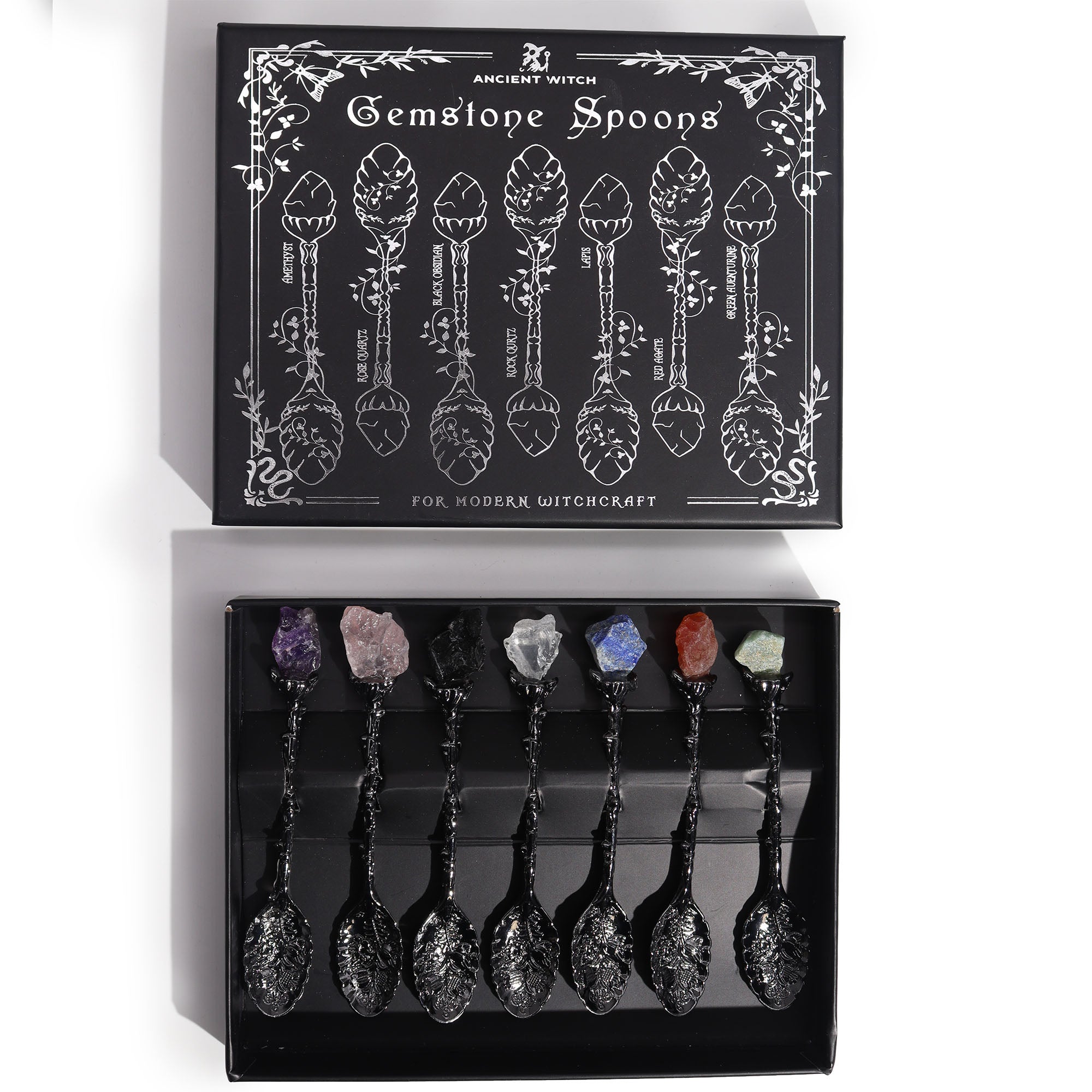 Set of 7 dark silver witch spoons with gemstone crystal handles, mystical themed decorative cutlery arranged together.