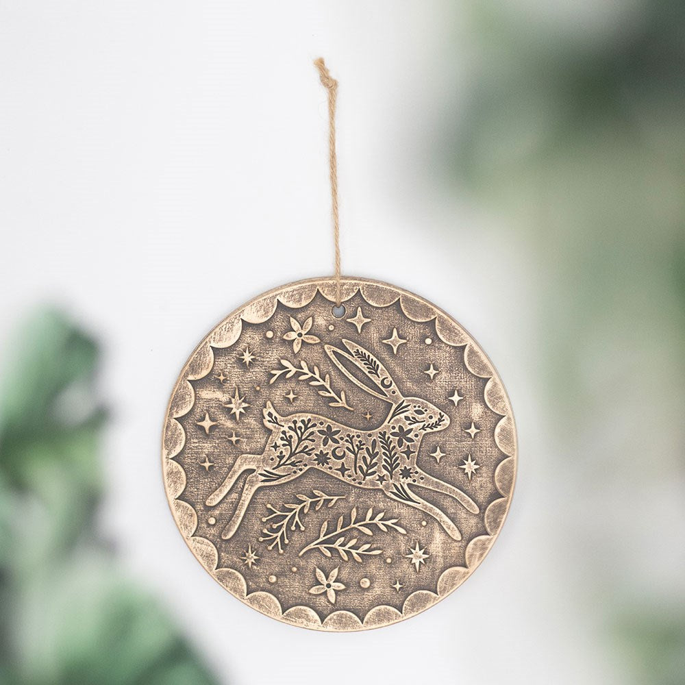 Round bronze effect terracotta hanging plaque with leaping hare, floral and star design, suspended by jute twine against a soft white background