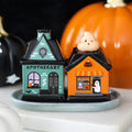 Ceramic Halloween salt and pepper shaker set shaped as a teal apothecary and orange Boo's Bakery building with ghost topper, on a matching tray, white background

