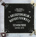Black 70x70cm talking board altar cloth with white alphabet, numbers, sun, moon, star and pentagram details, styled with crystals, candles and a sage bundle