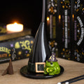 Black resin witch hat incense cone holder with a green magic toad figurine wearing a purple star and moon wizard hat, styled with spell books and a lit candle