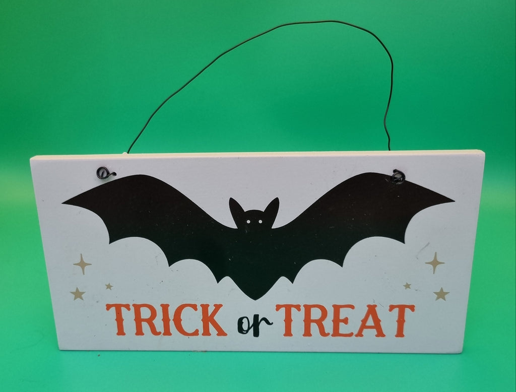 White wooden hanging sign with black bat silhouette and orange Trick or Treat text, decorated with gold stars, hung with black wire