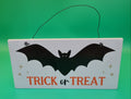 White wooden hanging sign with black bat silhouette and orange Trick or Treat text, decorated with gold stars, hung with black wire