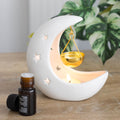 White ceramic crescent moon oil burner and wax melter with celestial-inspired decorative design.