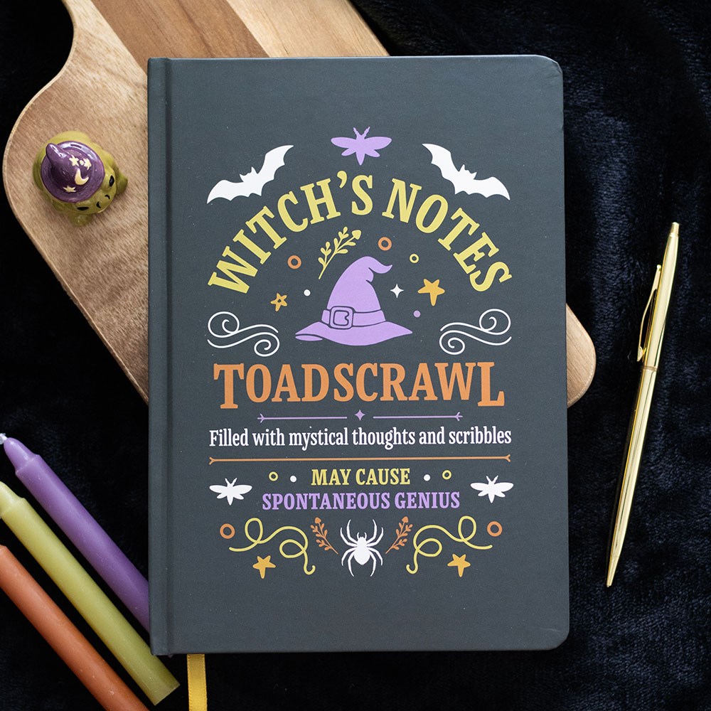 Dark grey A5 lined notebook with Witch's Notes Toadscrawl cover design featuring a purple witch hat, bats and spider, styled with candles and a gold pen