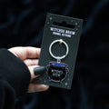 Metal keyring featuring a miniature cauldron charm with “Witches Brew” design and attached keyring loop.