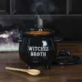 Black ceramic cauldron-shaped soup bowl with Witches Broth text and lid, filled with soup and styled on a dark wooden surface with a wooden broom spoon and amethyst crystals